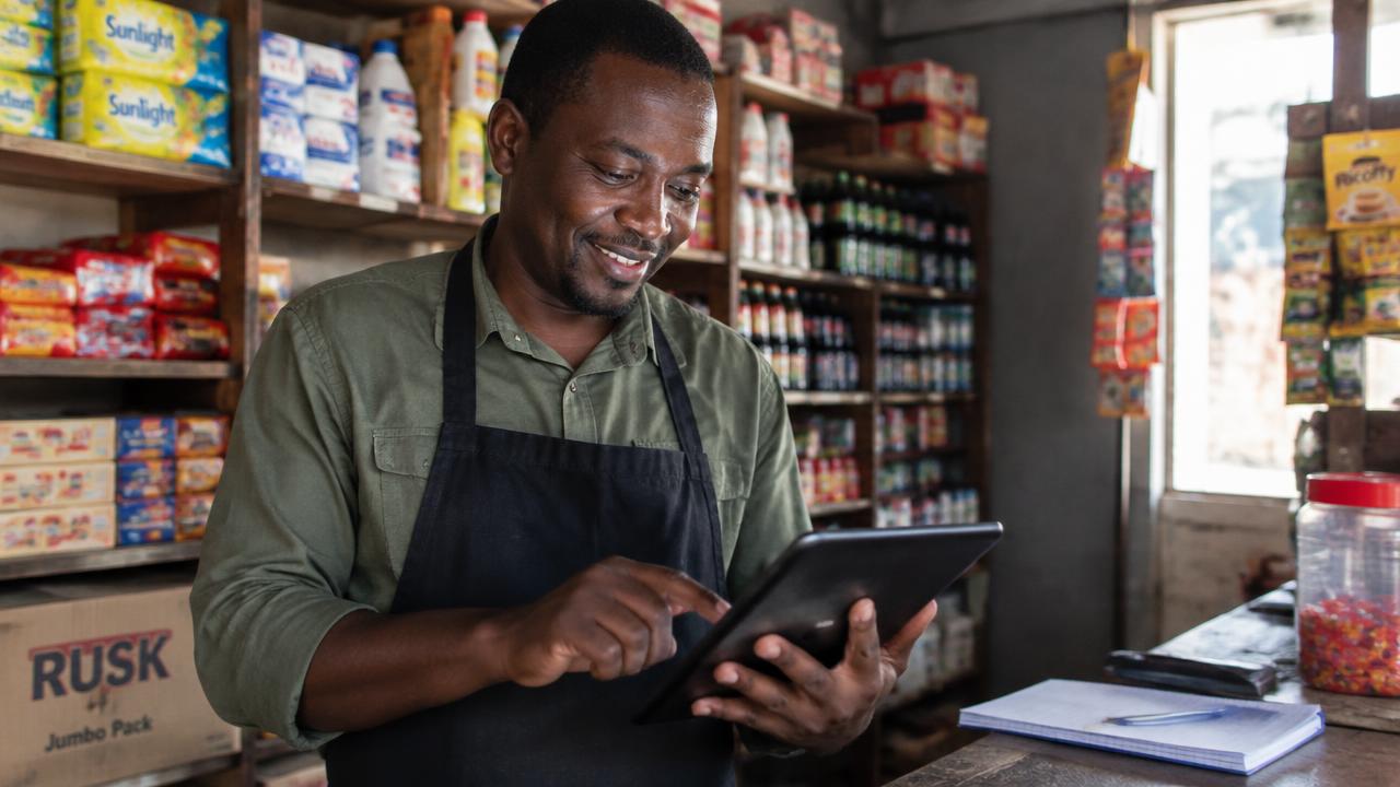 Shop owner listing products on a tablet in his store